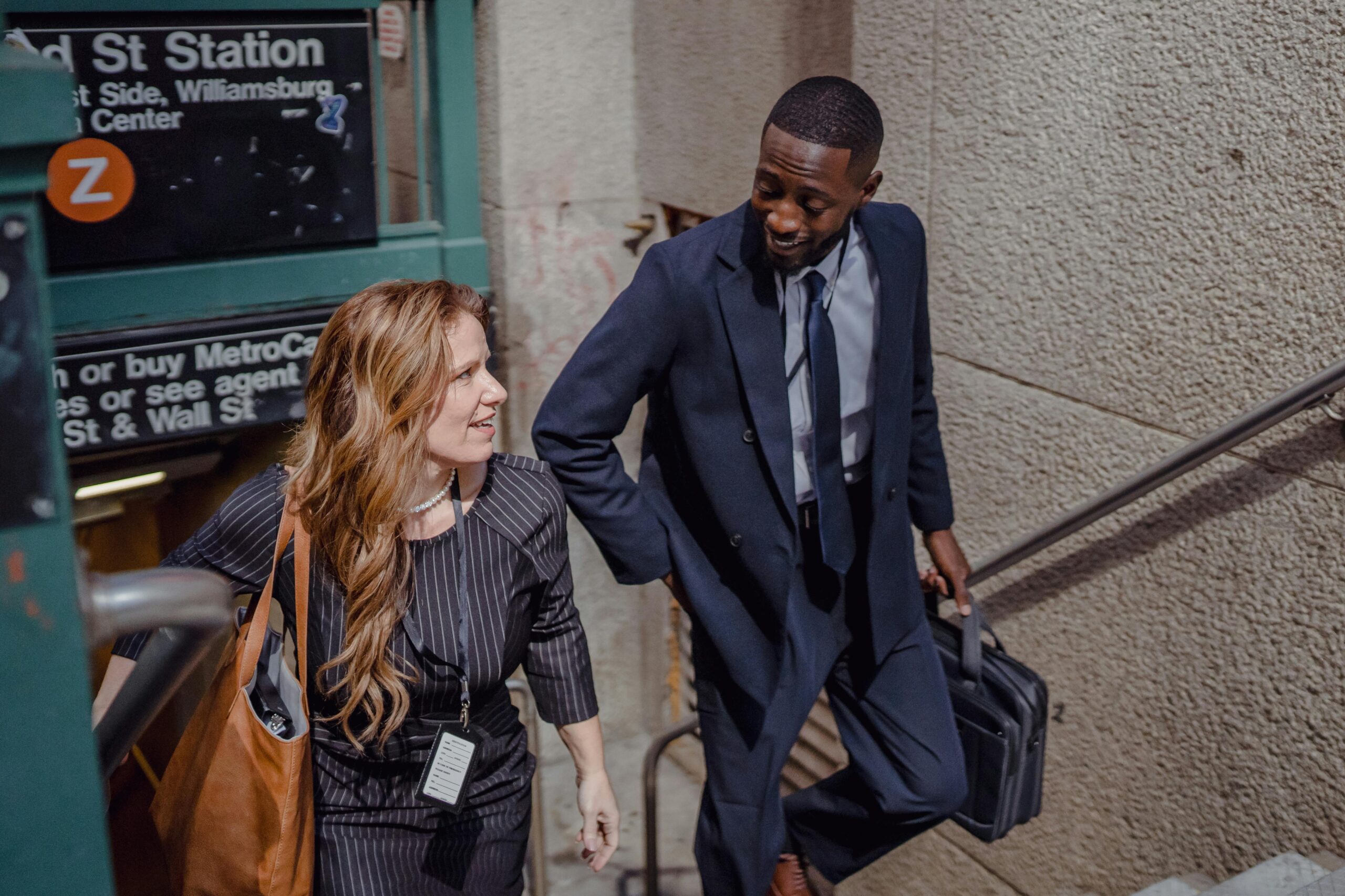 Two business professionals talking while exiting a New York City subway station.