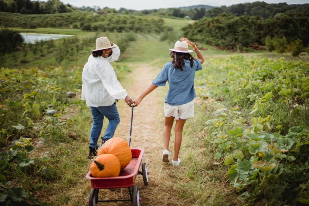 A mother and daughter enjoy harvesting pumpkins on a beautiful fall day outdoors.