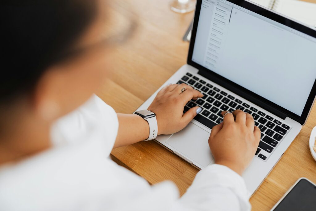 High angle shot of a person typing on a laptop, focused on hands and keyboard.