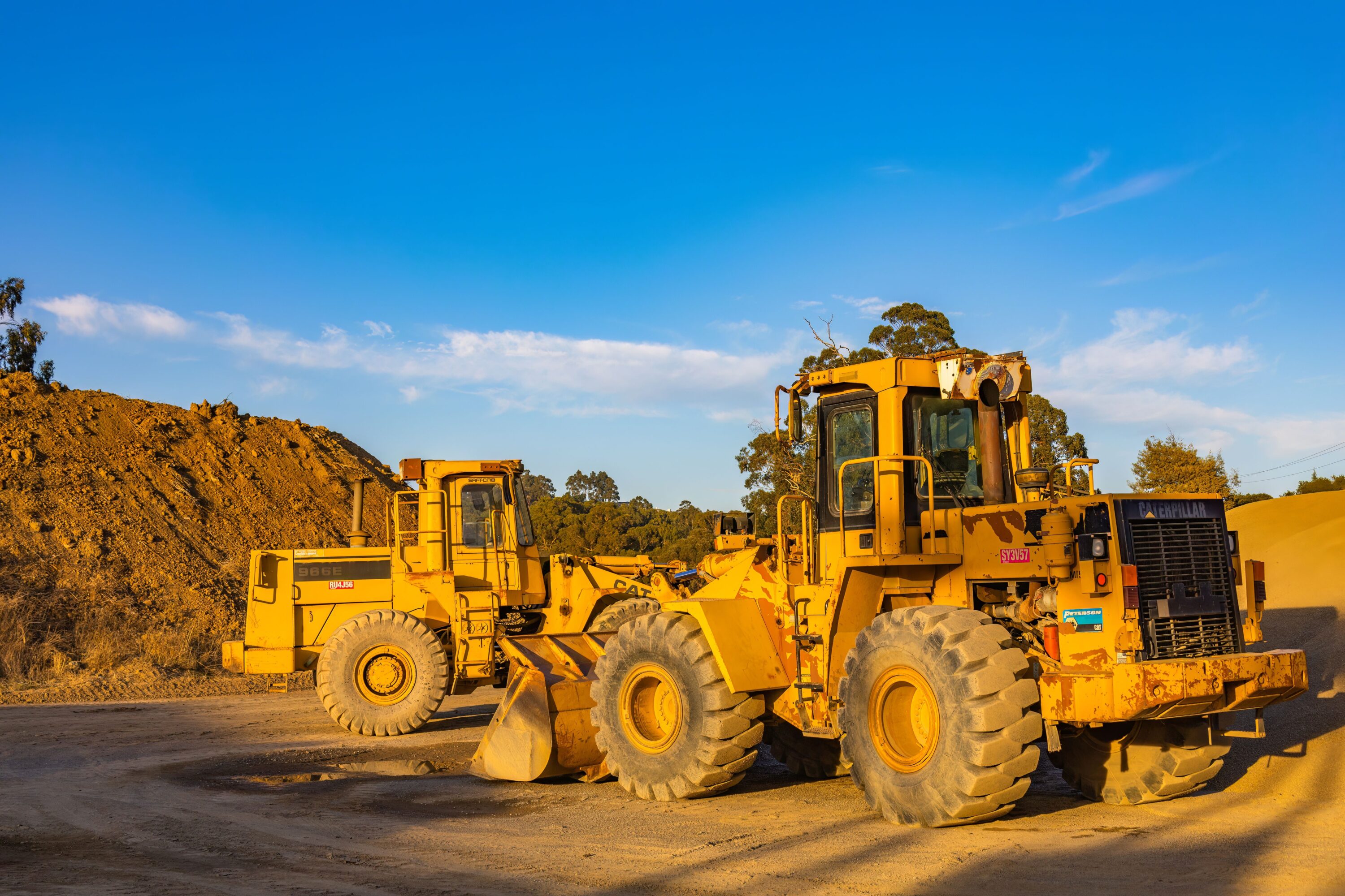 Heavy-duty bulldozers parked at a construction site under bright blue skies, showcasing industrial machinery.
